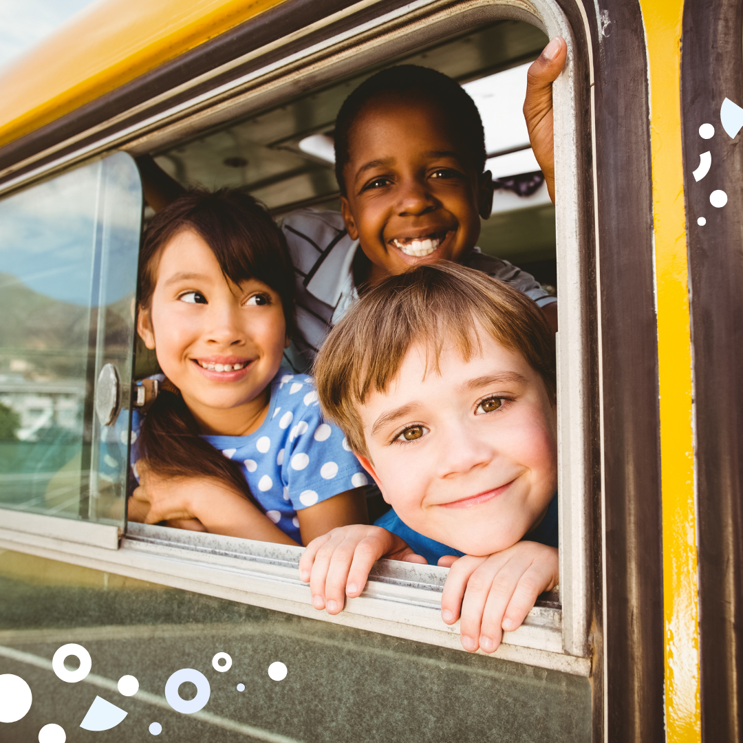 three elementary school students looking out school bus window