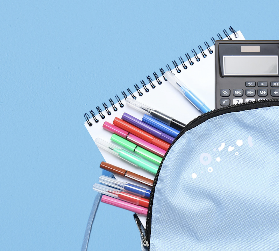light blue backpack on a blue background with a notebook, calculator and bright multicolored pens spilling out of it.