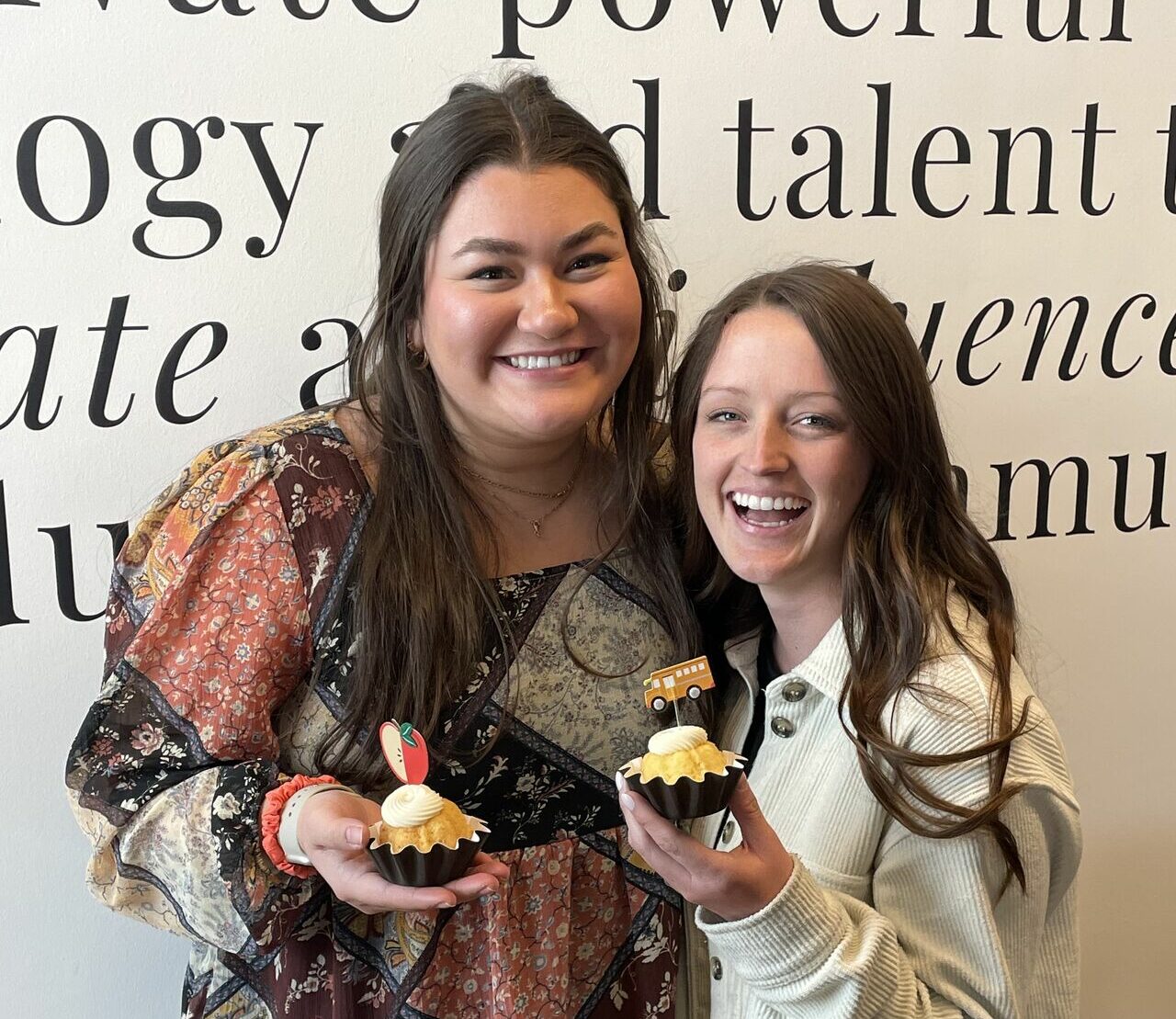 two female professionals celebrating with cupcakes